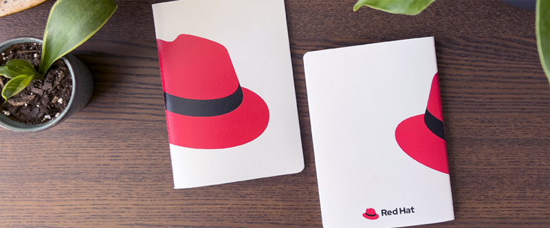 Photo of Red Hat branded notebooks with the hat on the cover.