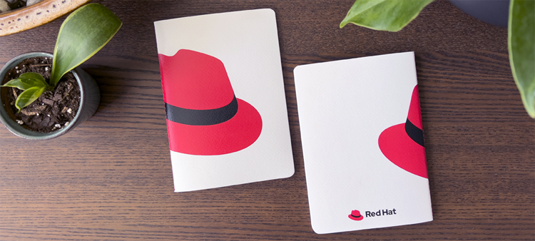 Photo of Red Hat branded notebooks with the hat on the cover.